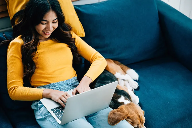 Mujer con su perro revisando su portátil