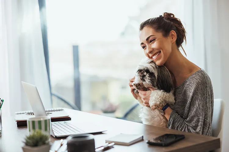 Mujer con su perro revisando su portátil