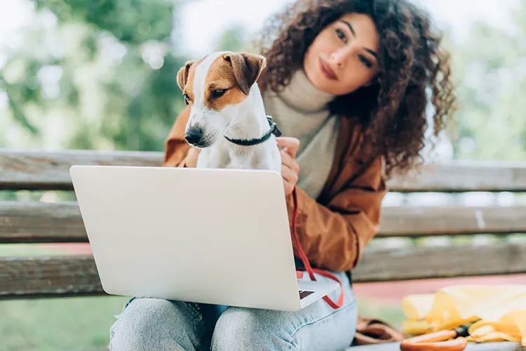 Mujer con su perro frente a su portátil