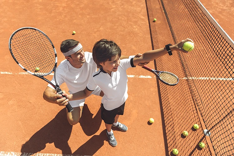 Niño aprendiendo tenis de campo