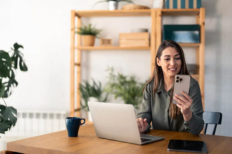 Pareja frente a su computador y revisando su celular