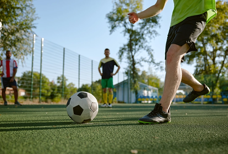 Personas jugando en cancha sintética de futbol