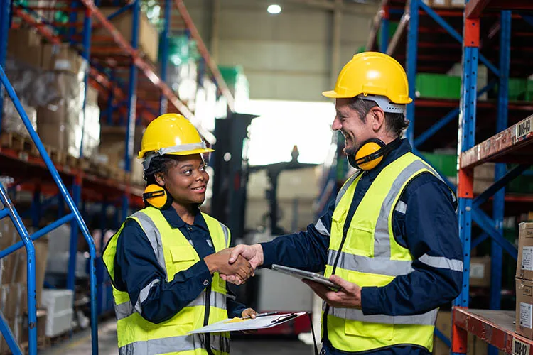 Personas trabajando en bodega y dándose la mano