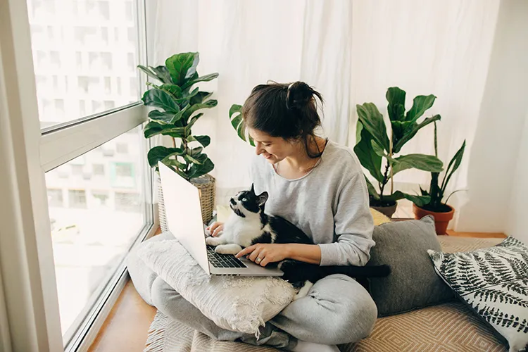 Mujer sentada con gato sobre teclado de computador