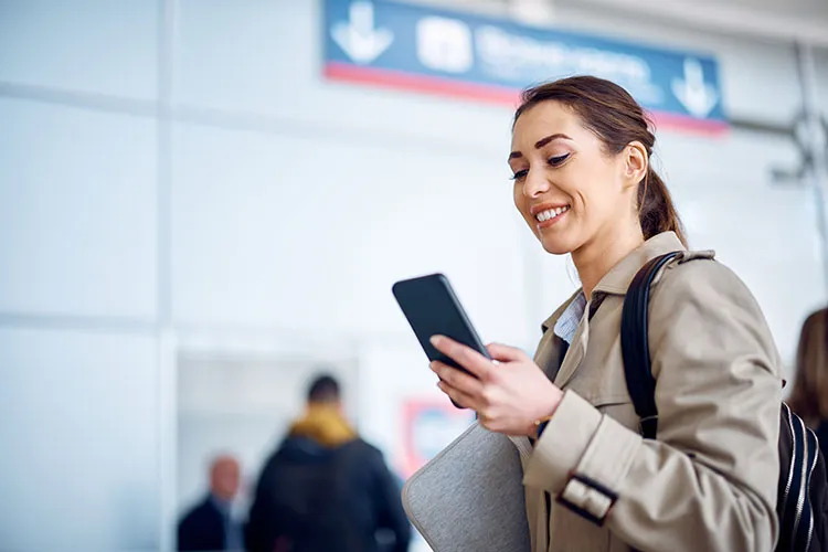 Mujer viendo su celular en el aeropuerto