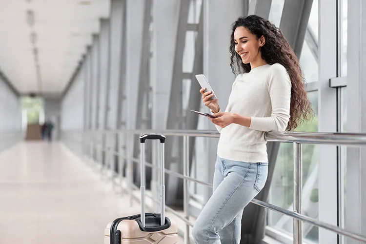 Mujer viendo su celular en el aeropuerto