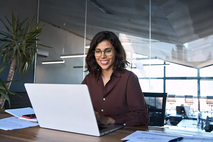 Mujer trabajando sonriente frente a computador