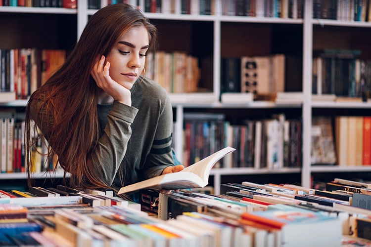 Mujer joven leyendo en biblioteca