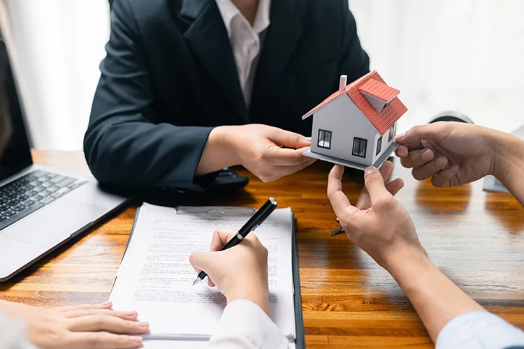 Manos sosteniendo maqueta de casa para servicio postventa