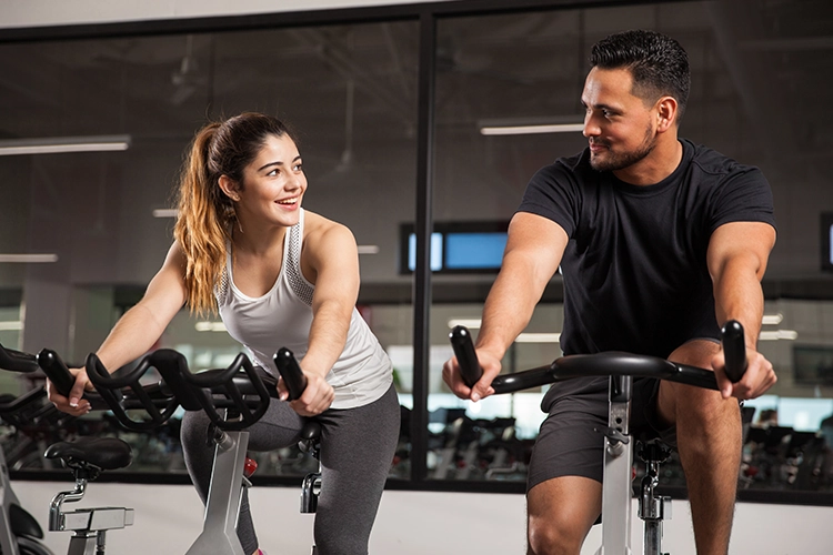 Hombre y mujer haciendo bicicleta en gimnasio