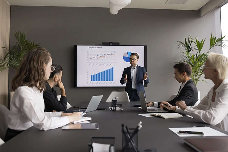 Grupo de trabajo hablando con unos datos en un televisor