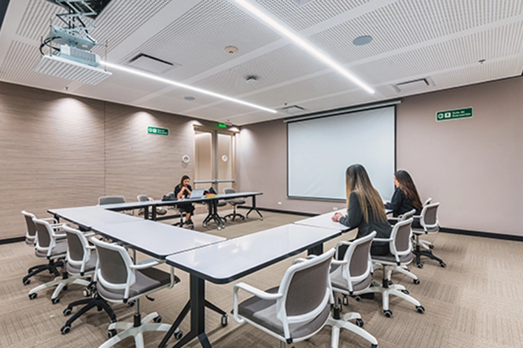 Sala con una mesa cuadrada y sillas, tres mujeres sentadas conversando