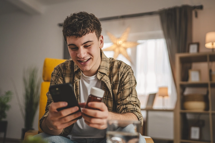 Hombre sostiene una medicina mientras ve el celular