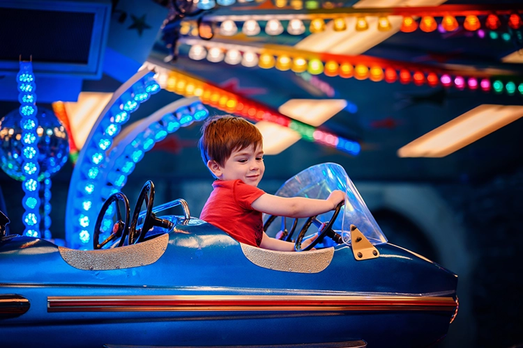 Niño en un parque de diversión manejando un carrito.