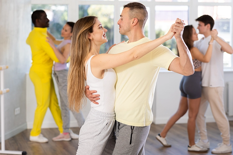 Dos personas jóvenes bailan en el taller de bachata de Colsubsidio.