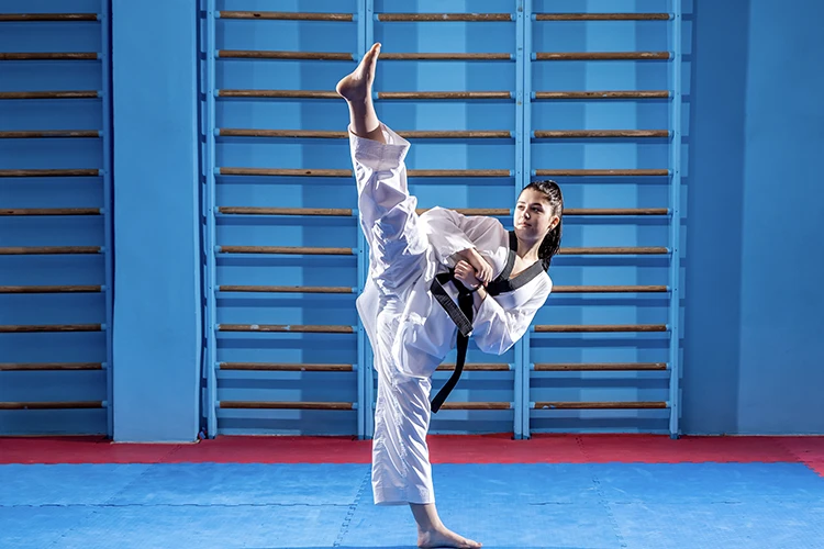 Una mujer jóven realizando una práctica de Taekwondo.