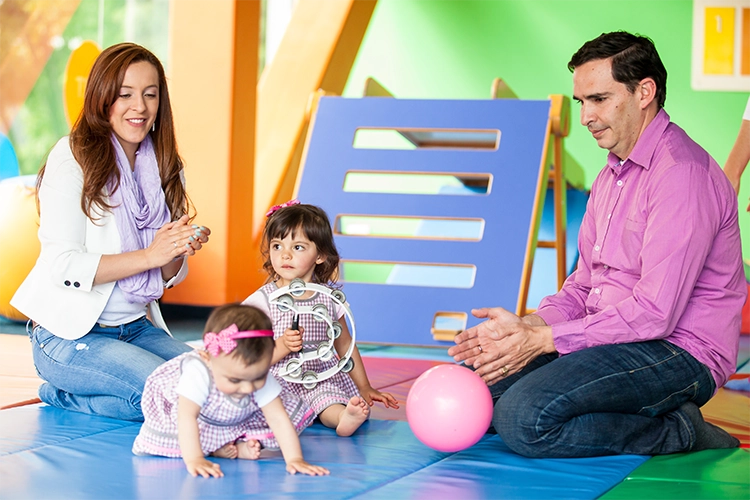 Padres de familia junto a sus dos hijas pequeñas en el curso de estimulación para bebés de Colsubsidio.