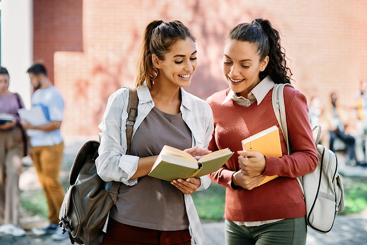 Dos estudiantes de universidad revisan un libro.