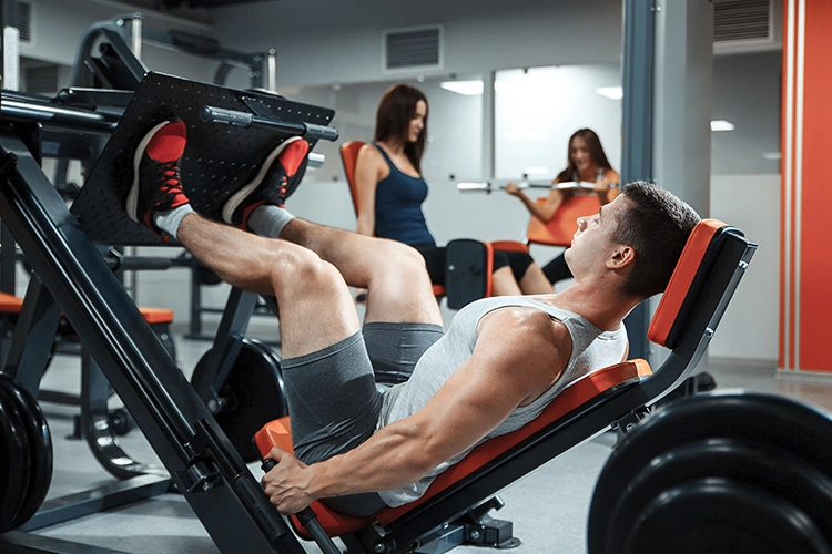 Varias personas en un gimnasio realizando diferentes ejercicios en máquinas.