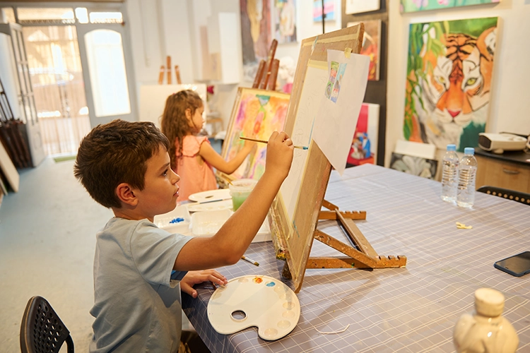 Un niño y una niña pintando en sus caballetes.