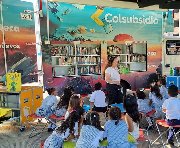 Profesora leyendo historias a los niños a través de la Biblioteca Móvil Colsubsidio.