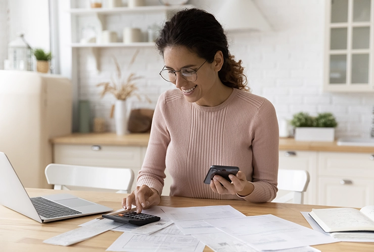 Mujer aprende tips financieros en línea, y usa la calculadora para medir sus tasa de interés.