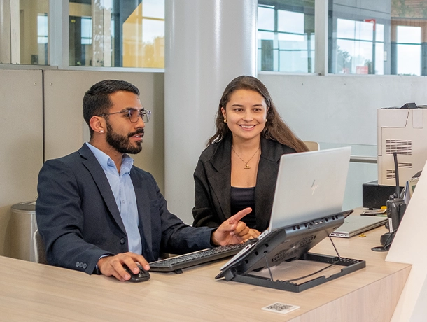 Hombre y mujer sentados frente a un computador