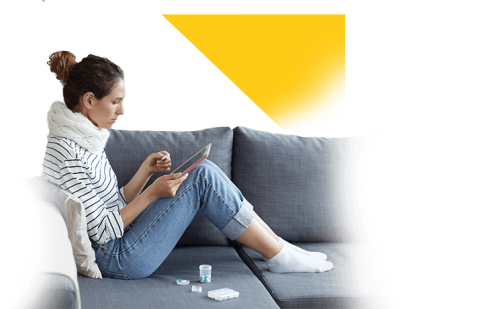 Mujer recostada en el sofá con medicinas y viendo el celular